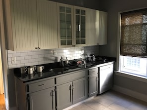 A kitchen with white cabinets, a black countertop, and a window with blinds. - 2-bedroom apartment in enchanting Milwaukee with AC comfort (Milwaukee)