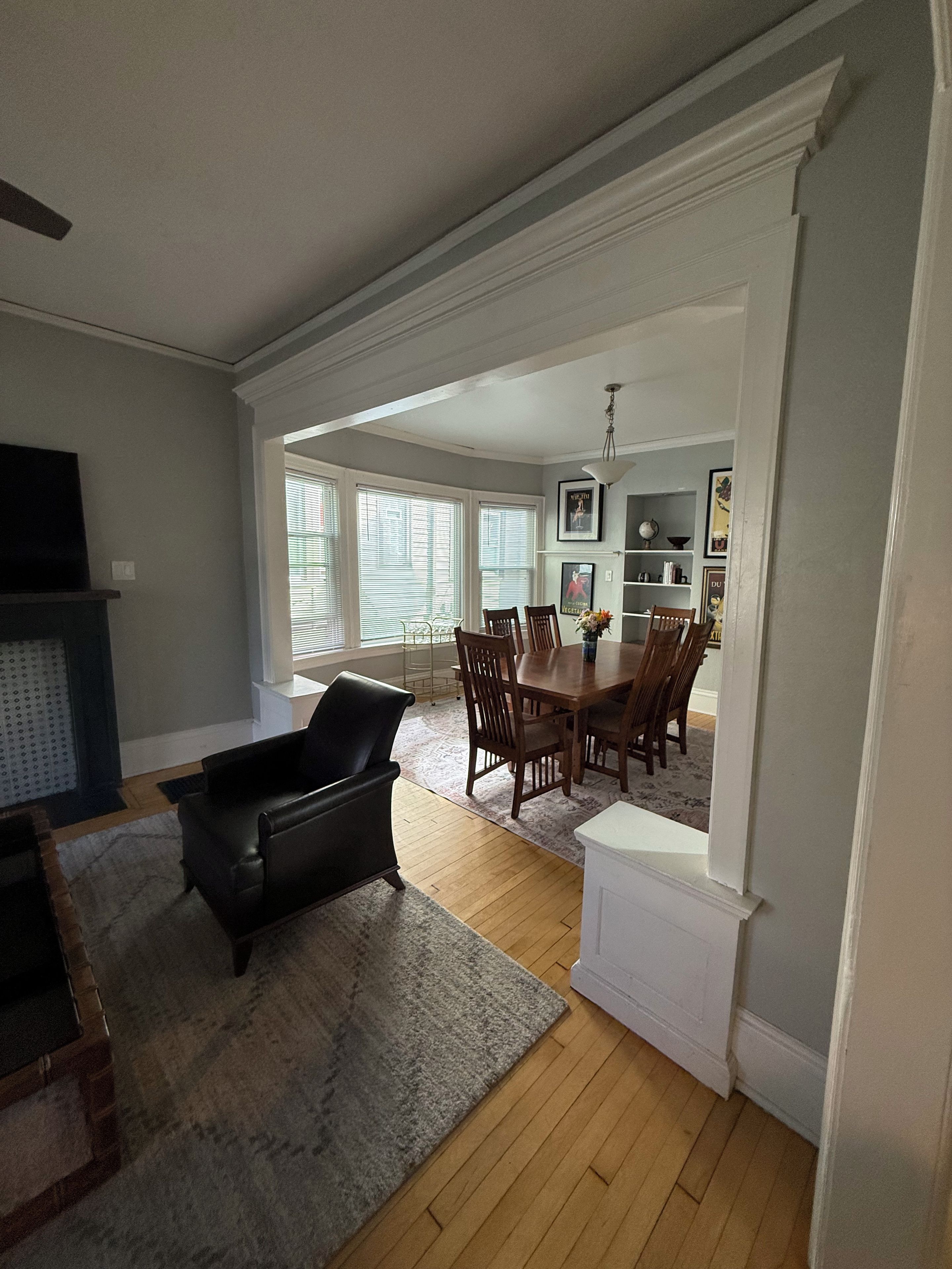 A spacious living area with a fireplace, a dining table with chairs, and a kitchen area in the background.