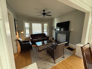 A living room with a fireplace, a sofa, a coffee table, and a television. - 2-bedroom apartment in enchanting Milwaukee with AC comfort (Milwaukee)