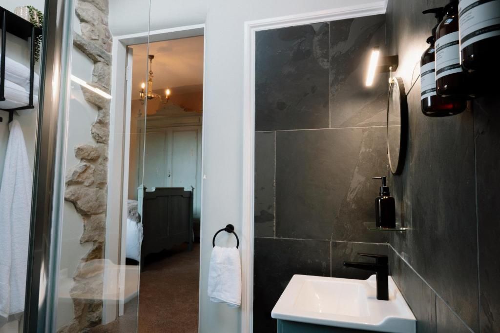 Une salle de bain moderne avec une douche à l’italienne en verre, un lavabo blanc et un robinet noir.