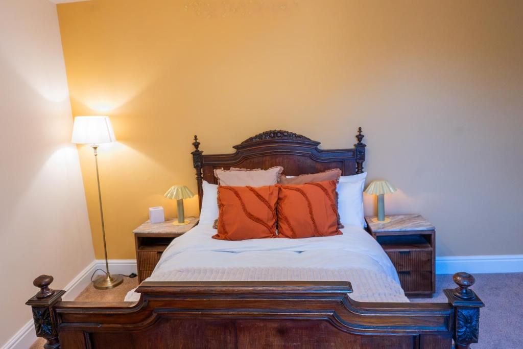 Un lit avec une tête de lit en bois, deux tables de chevet avec des lampes et un mur sobre.