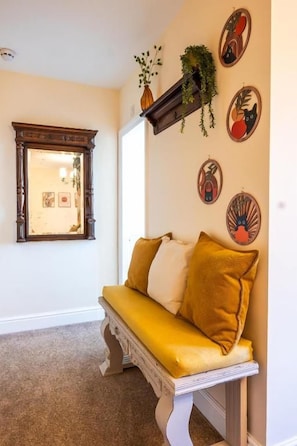 A room with a bench, a mirror, and wall art.