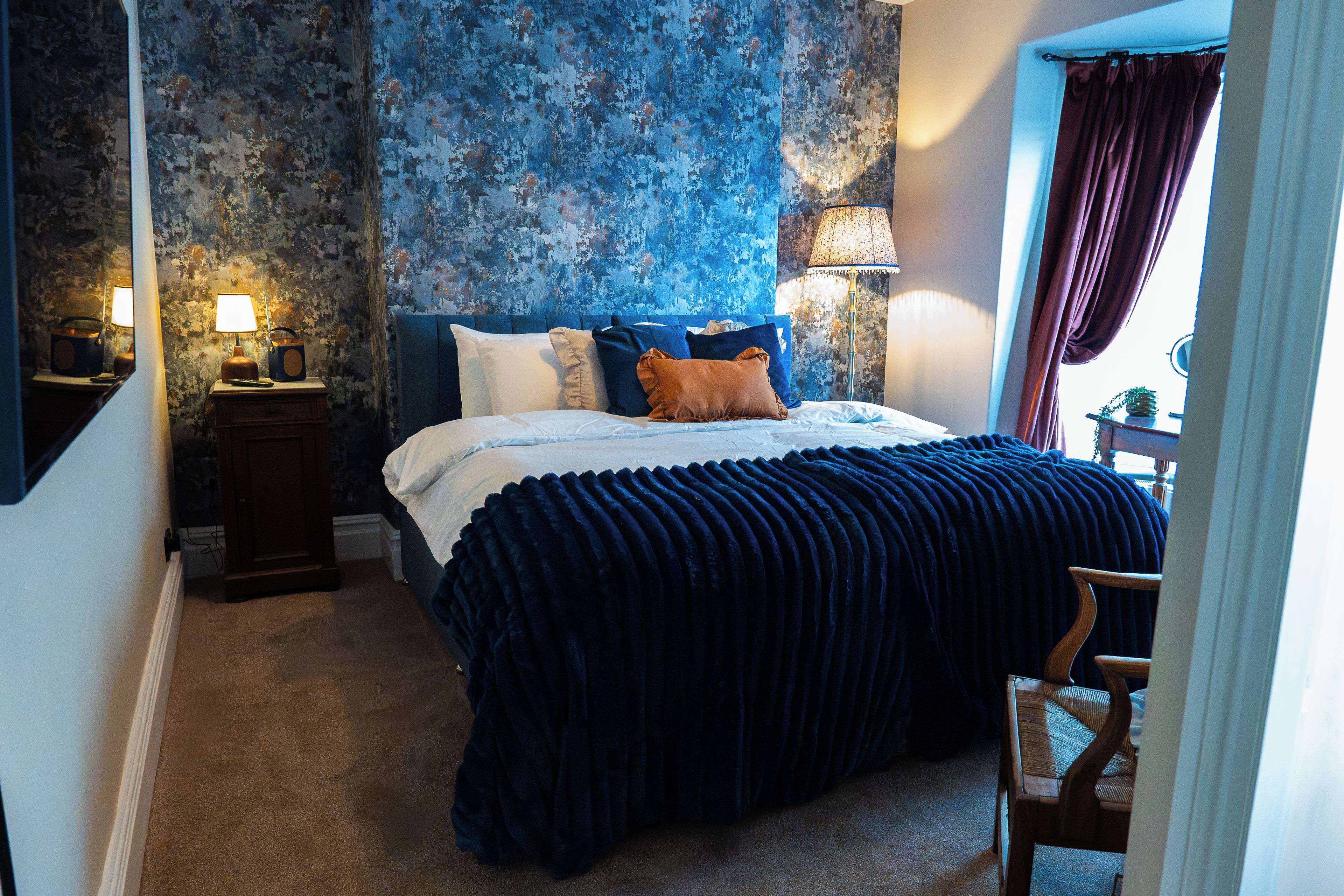 Une chambre à coucher avec un grand lit, une table de chevet, une lampe et une chaise.