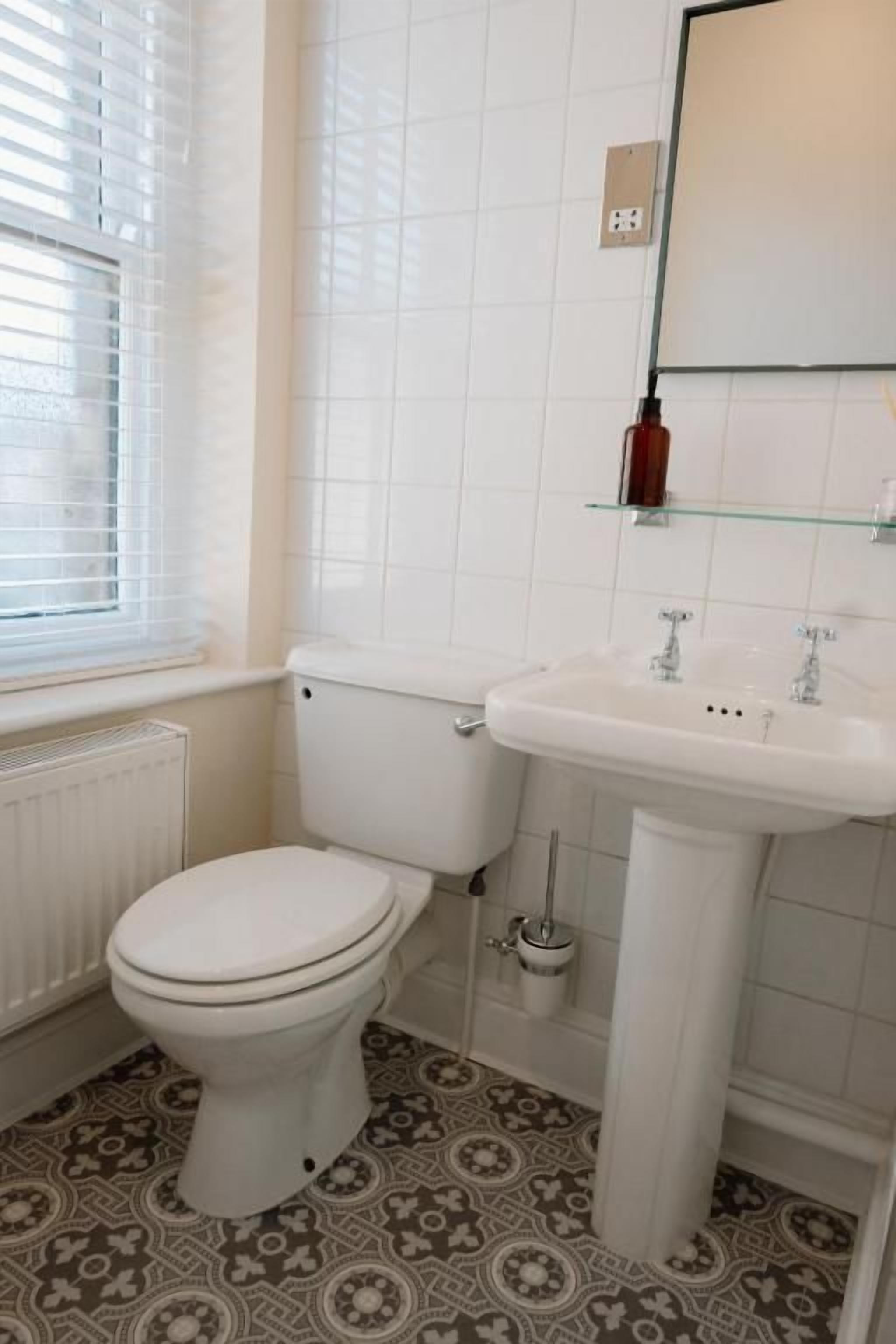 A bathroom with a toilet, sink, and a mirror.