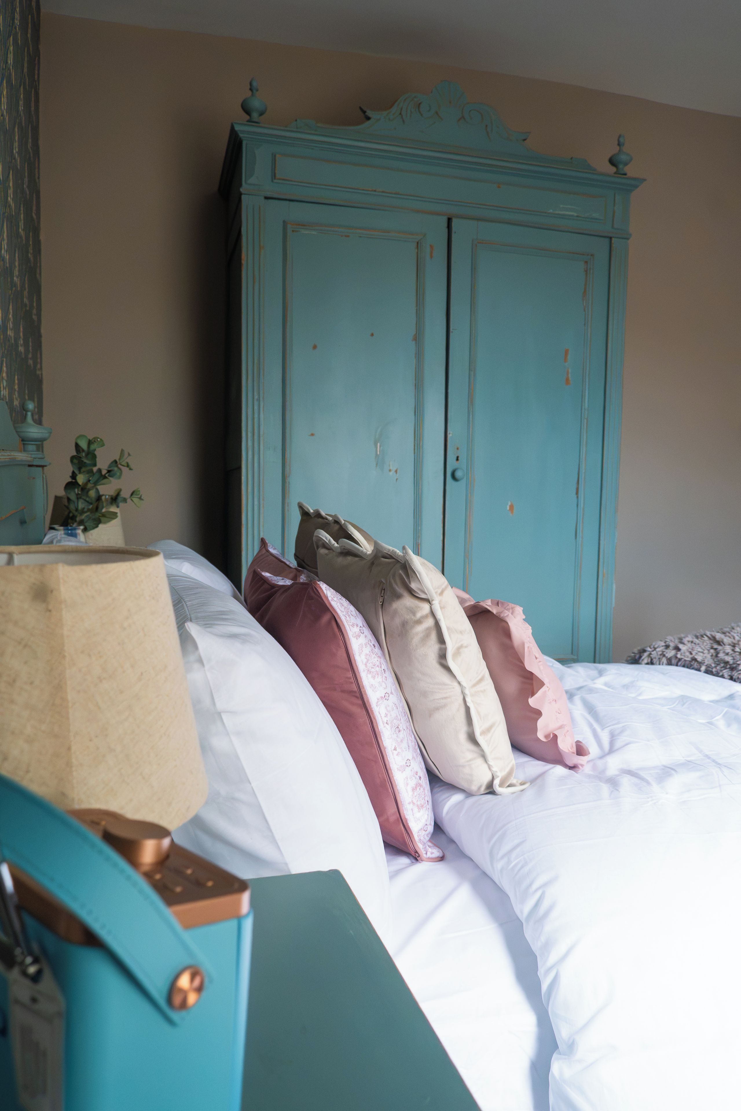 A bed with pillows and a blue cabinet in a room.