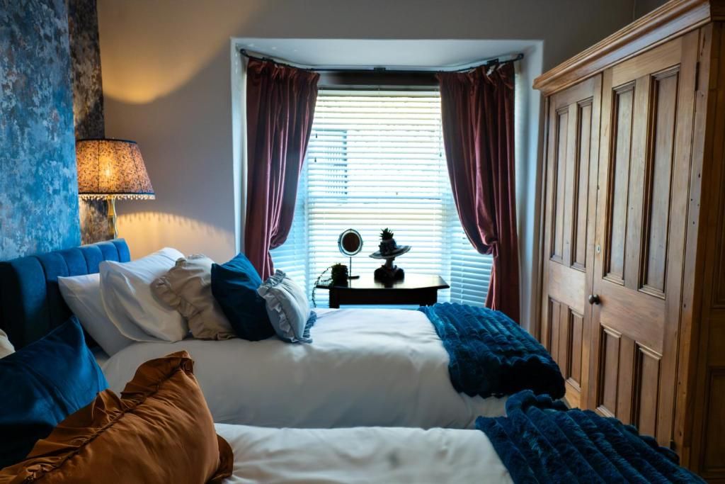 Une chambre avec deux lits, une table de chevet avec une lampe, un miroir et une armoire.