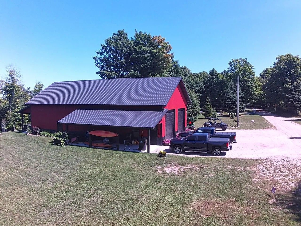 A red and black building with a covered area and a gravel driveway.