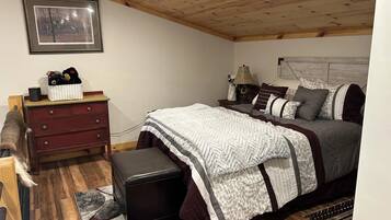 A bedroom with a bed, a dresser, a nightstand, and a framed picture on the wall.