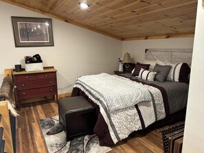 A bedroom with a bed, a dresser, a nightstand, and a framed picture on the wall.