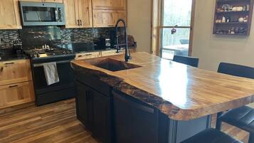 Una cocina con armarios de madera, una estufa negra y una isla con encimera de granito.