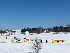 A snow-covered field with several small aircraft and a few people walking.