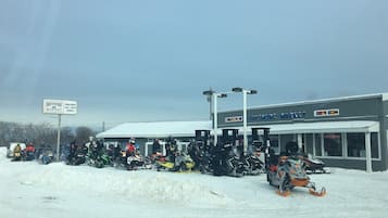 A snow-covered outdoor area with a building labeled "Bay Shore Market" and several snowmobiles parked in front.