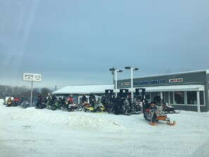 A snow-covered outdoor area with a building labeled "Bay Shore Market" and several snowmobiles parked in front.