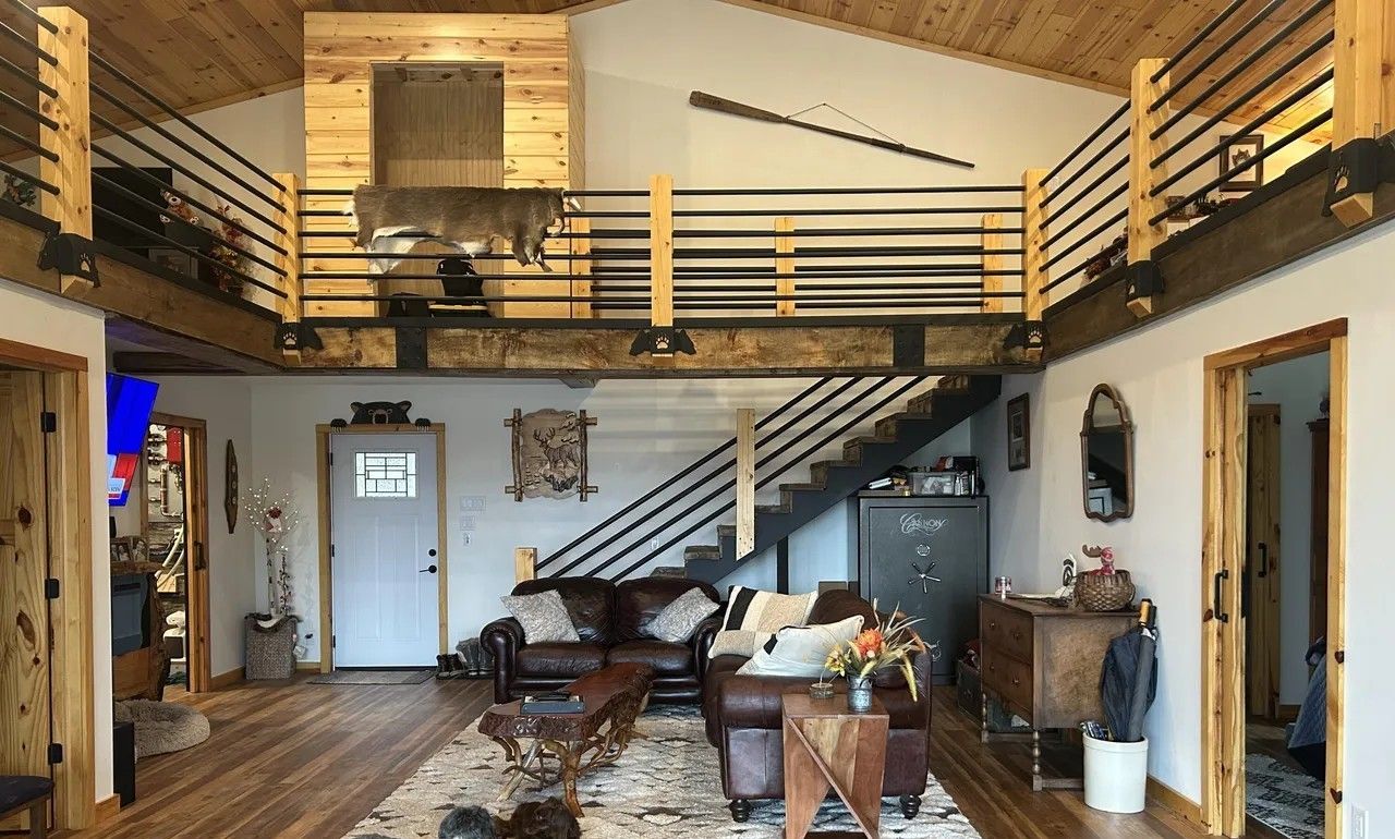 Amplio espacio tipo loft con techo alto, una escalera y un ventanal grande.