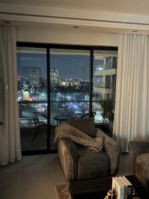 A modern living room with a sofa, a coffee table, and a view of a cityscape through large windows. - Gorgeous 1-bedroom apartment in Nairobi kilimani perfect for your stay (Nairobi)