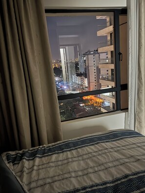 A bedroom with a window overlooking a cityscape at night. - Gorgeous 1-bedroom apartment in Nairobi kilimani perfect for your stay (Nairobi)