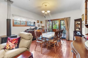 A dining area with a large table, chairs, and a view through a glass door.