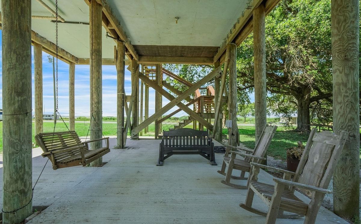 Un pavillon en bois installé à l’extérieur, équipé d’une balançoire, d’un banc et de chaises.