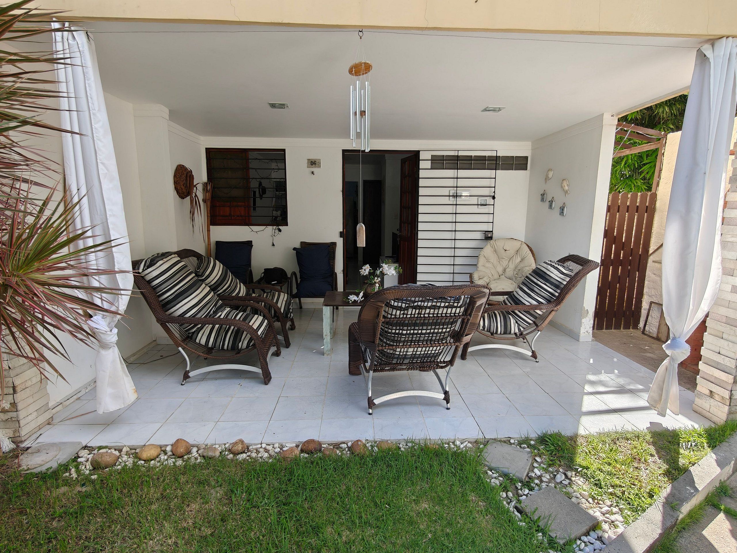 A covered patio area with wicker furniture, a table, and a hanging light fixture.