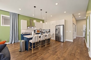 A modern kitchen with a central island, stainless steel appliances, and pendant lighting. - Retro Retreat | Hot Tub • Firepit • Near Lucas Oil (Indianapolis)