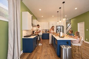 A modern kitchen with a central island, stainless steel appliances, and pendant lighting. - Retro Retreat | Hot Tub • Firepit • Near Lucas Oil (Indianapolis)