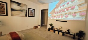 A room with a projector displaying a hotel exterior, a framed quote on the wall, and a small desk with a plant. - Vrbo Property (San Marcos)
