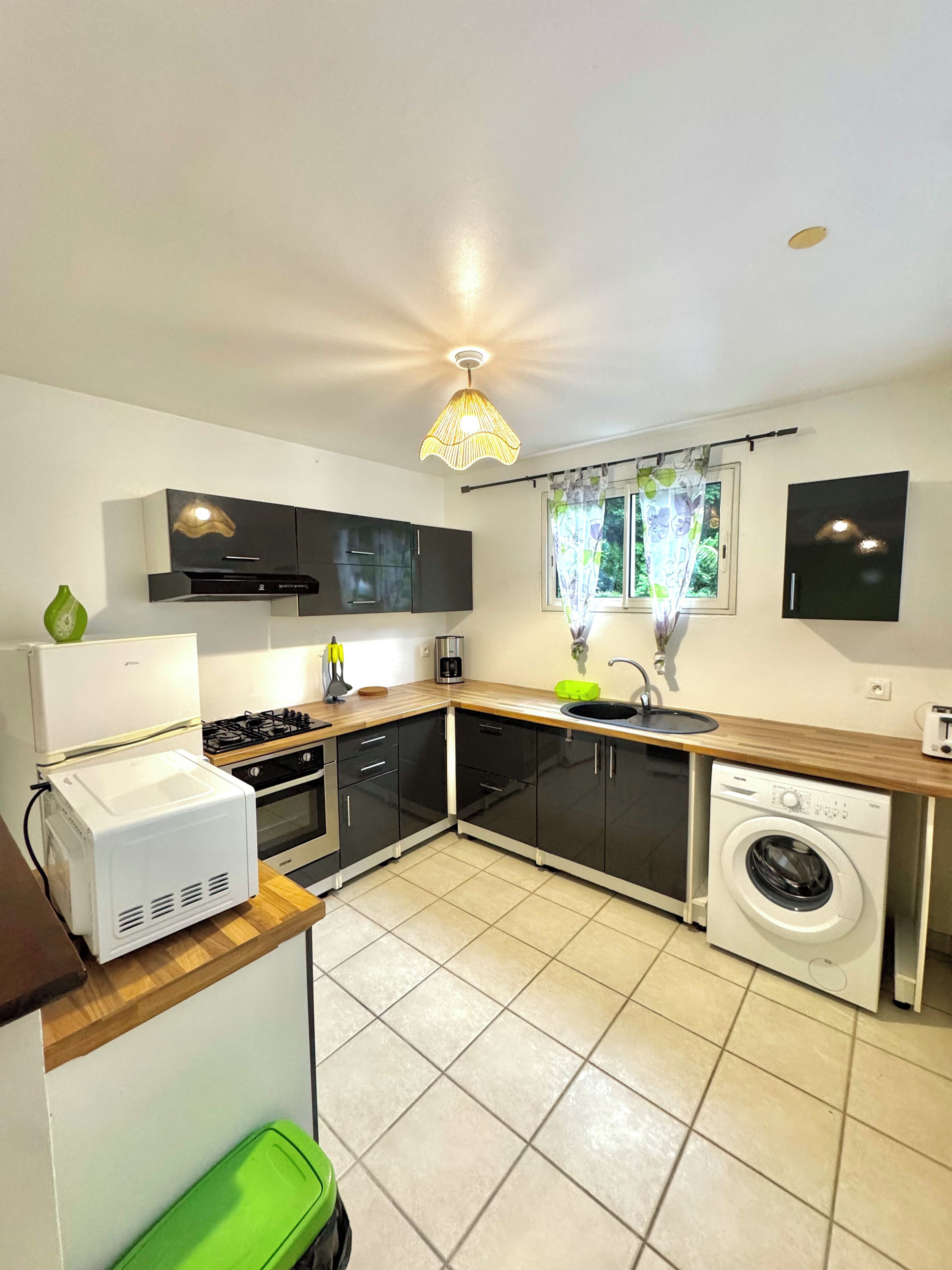 A compact kitchen with a gas stove, a built-in oven, a washing machine, and a sink.