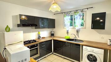 A compact kitchen with a gas stove, a built-in oven, a washing machine, and a sink.