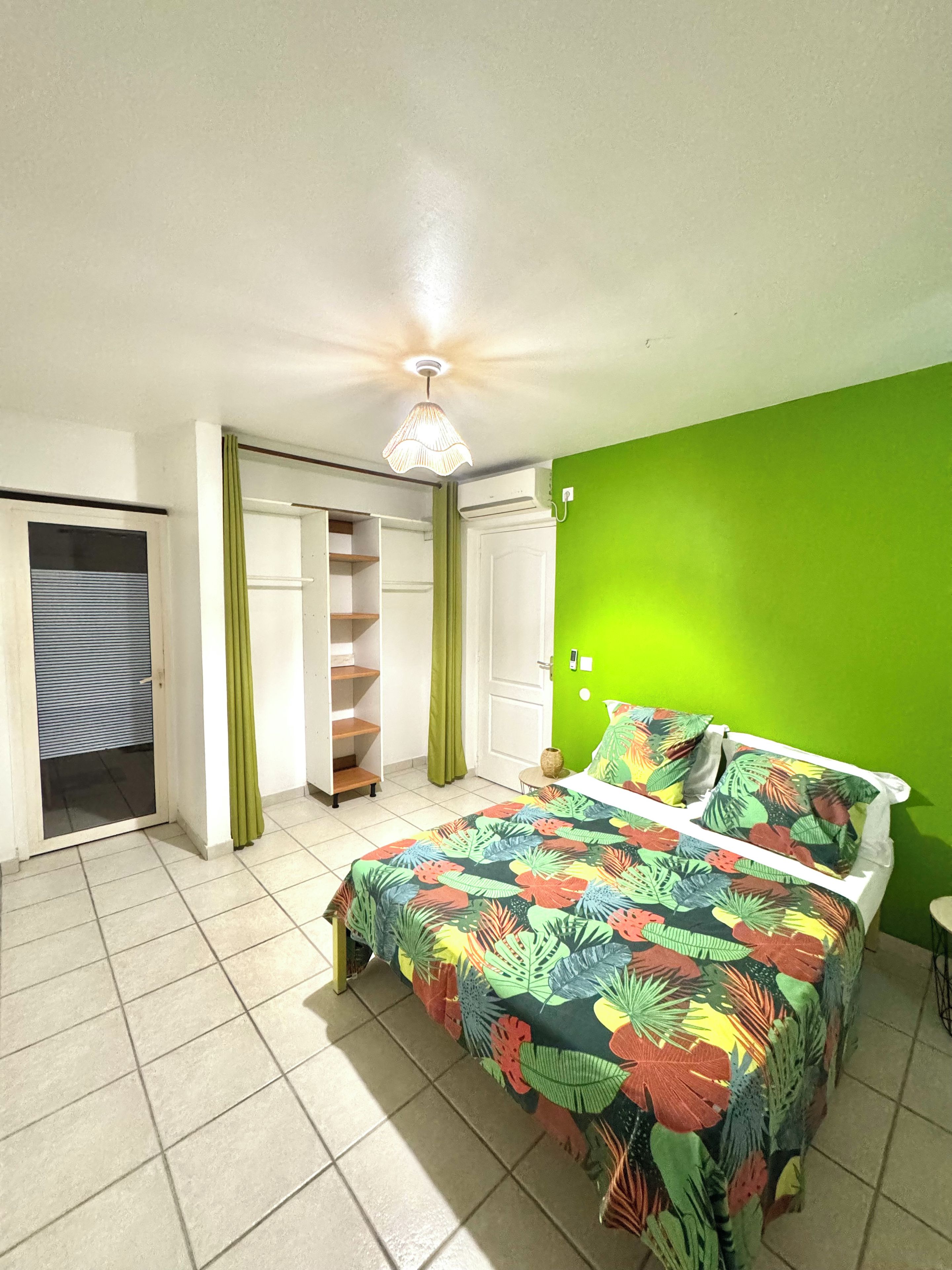 A bedroom with a bed, a wardrobe, a green wall, and a ceiling fan.