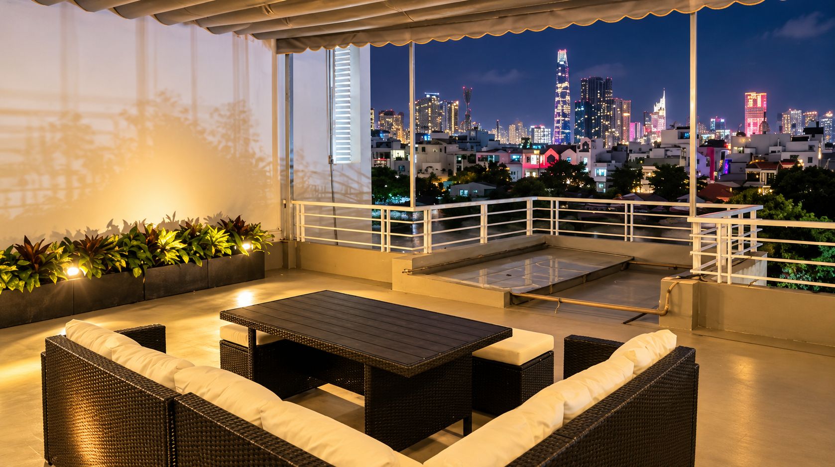 Eine Dachterrasse mit Gartenmöbeln, Blick auf eine nächtliche Skyline und einer Brüstung.