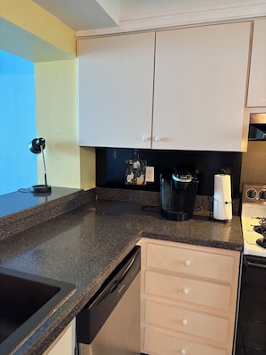 A kitchen with a dishwasher, a coffee maker, and a kettle on the counter. - Lovely 2-bedroom condo on the beach, fully furnished. (Satellite Beach)