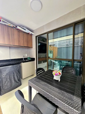 Une cuisine compacte avec des meubles en bois, un plan de travail noir et un coin repas comprenant une table et des chaises.
