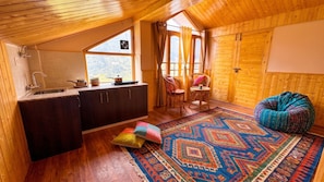 Interior acogedor de una cabaña con cocina, comedor y un amplio ventanal que ofrece vistas al exterior.