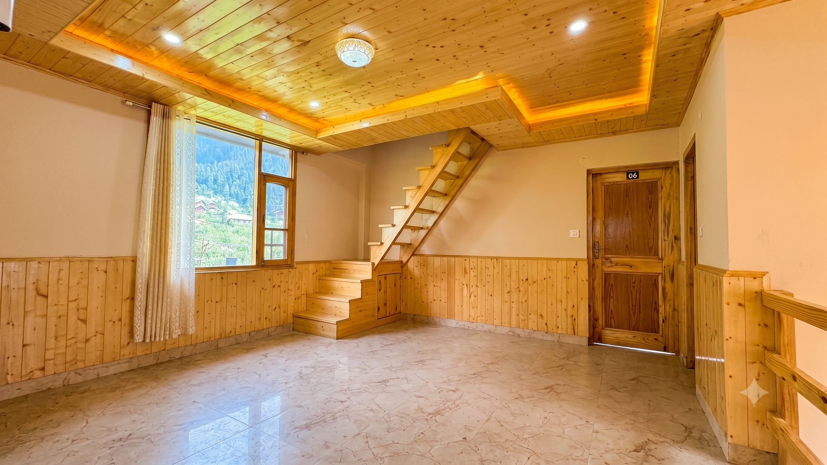 Una habitación con escalera de madera, un ventanal con vista a vegetación y una puerta con el número 06.