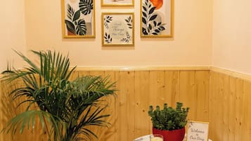 A hallway with wooden paneling, a potted plant, a small table with a candle, and framed artwork on the wall.