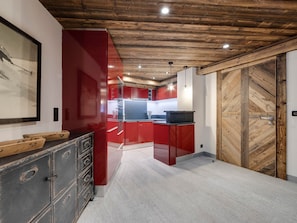 Una cocina moderna con armarios rojos, techo de madera y una puerta grande de madera.