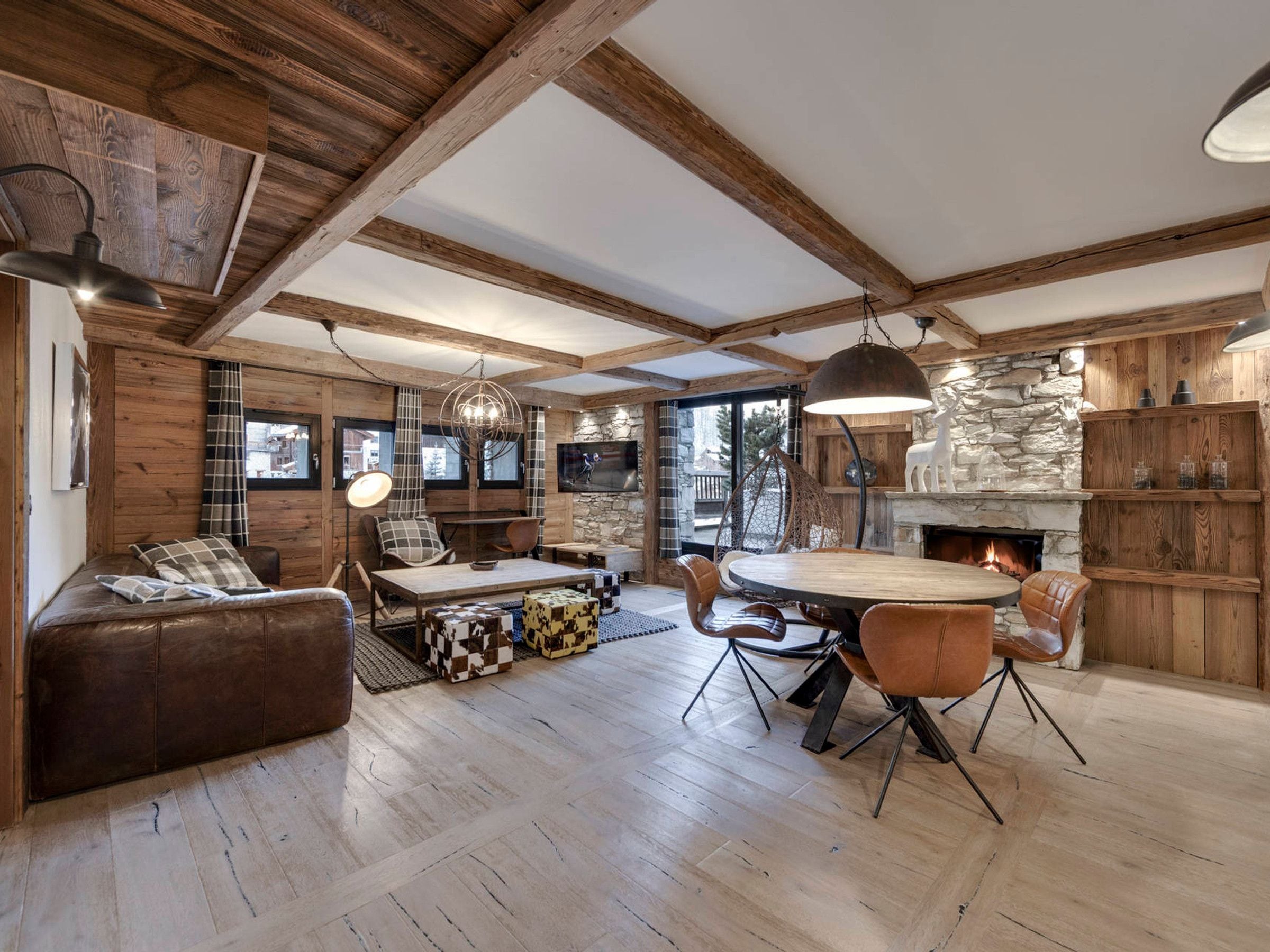 A spacious living area with a fireplace, wooden beams, and a stone wall.