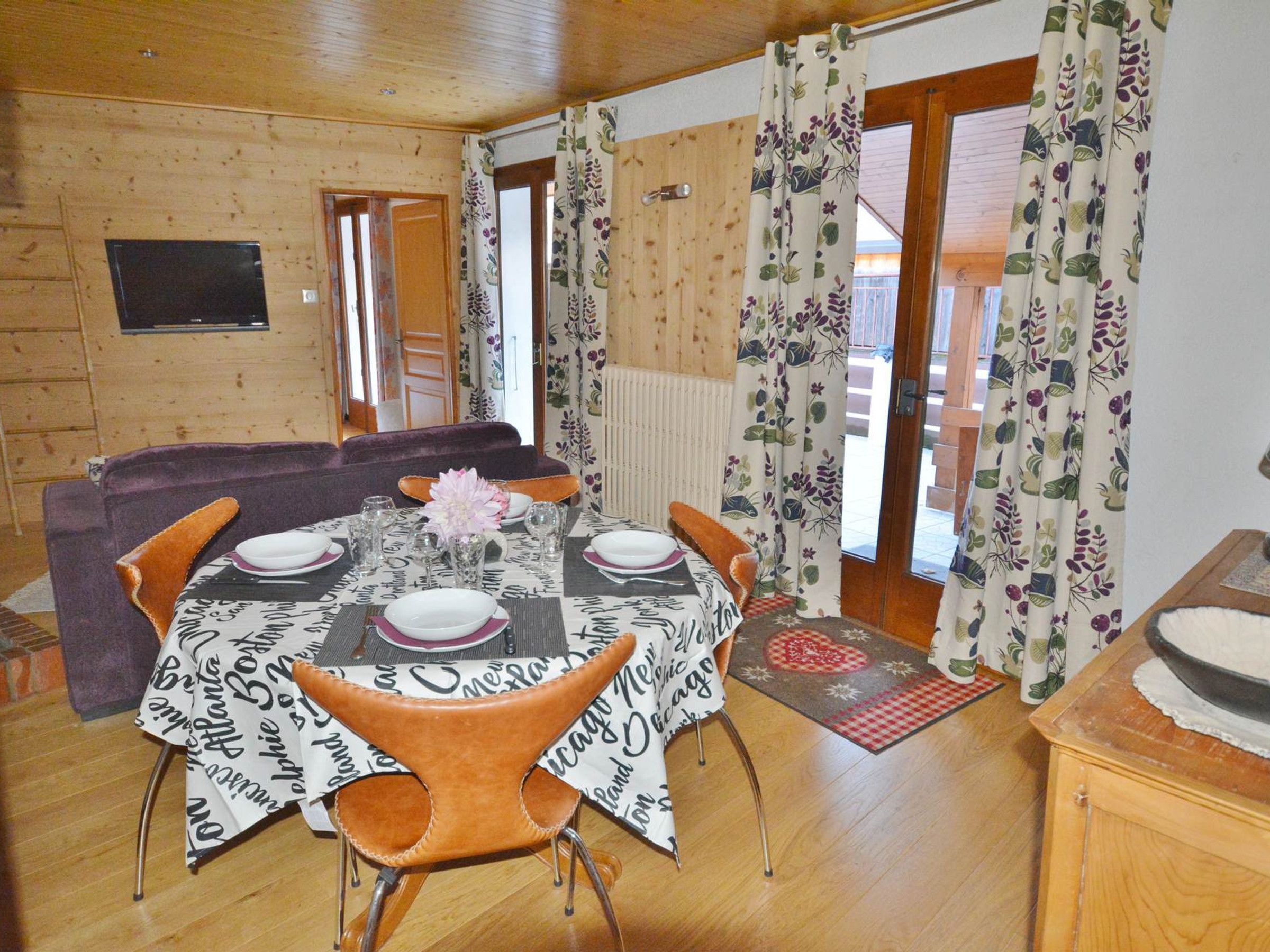 A dining area with a table set for four, a sofa, and a view of the outdoors.