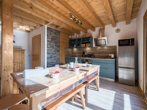A modern kitchen with wooden beams, a central island, and built-in appliances. - Chalet panoramic view - 9 guests (La Toussuire)