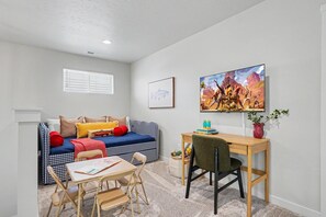 A compact living space with a sofa, a small table, and a desk. - 5BR/3BA Gem State Getaway | Game Room + Yard (Nampa)