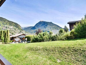 Une vue sur une montagne, avec une maison au premier plan et un village en arrière-plan.