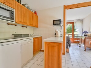 A kitchen with wooden cabinets, a microwave, a kettle, and a dishwasher. - Central apartment in Morzine - 5 guests (Morzine)