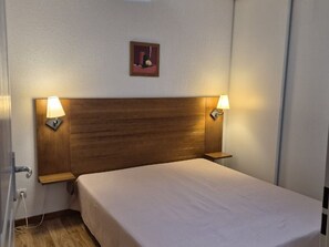 A hotel room with a wooden headboard, two bedside lamps, a small framed picture on the wall, and a plain bedspread. - Quiet duplex apartment - 8 guests (Orcières Merlette)