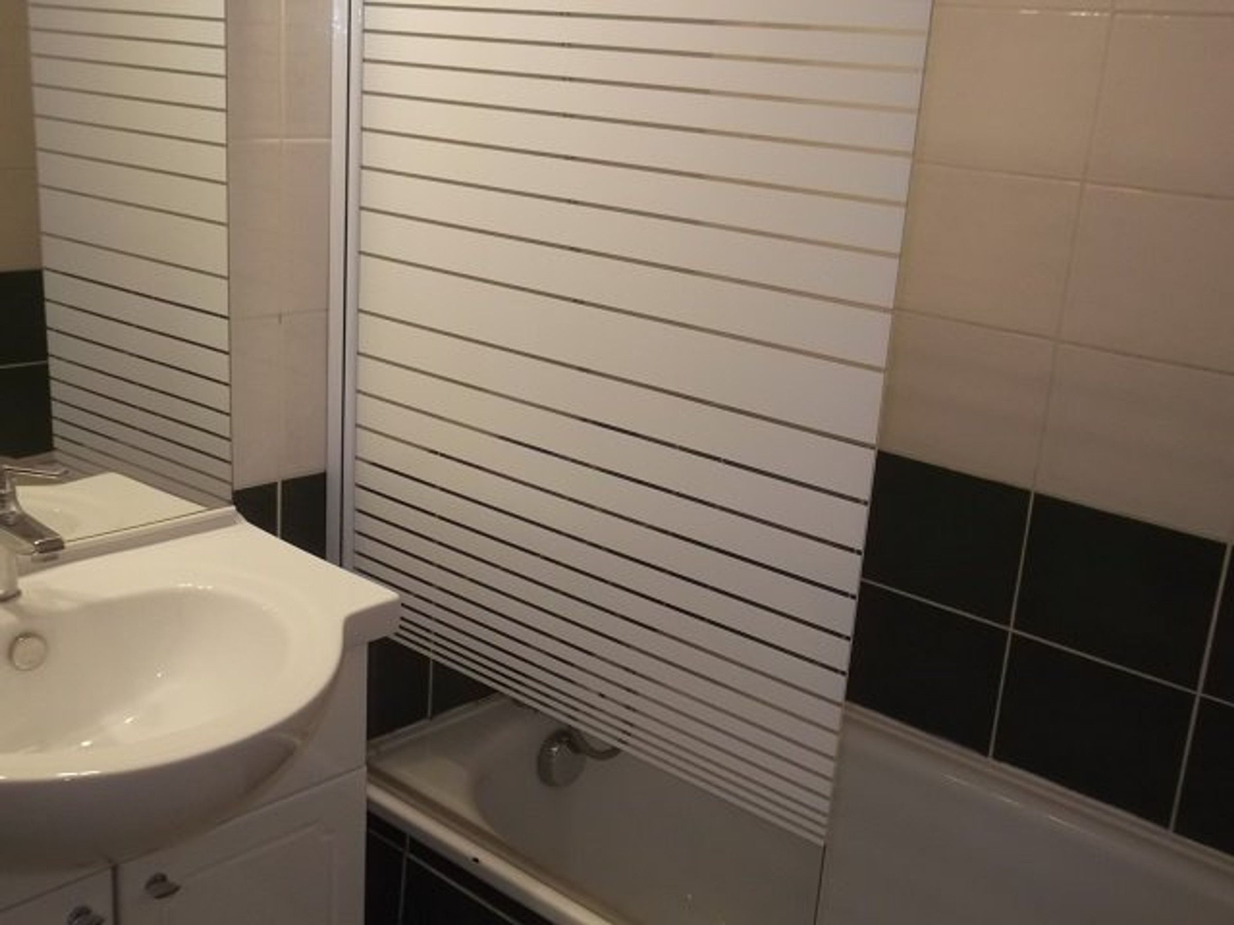 Une salle de bain avec un lavabo blanc, un miroir et une baignoire.