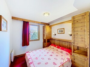 A bedroom with a bed, a window with a view, wooden paneling, and a wall-mounted light fixture. - Comfortable apartment, pets welcome - 4 guests (La Toussuire)