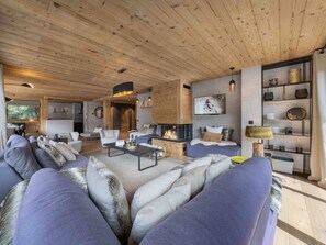 Un salon moderne avec une cheminée, des sièges confortables et un téléviseur.