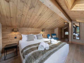 A wooden-paneled bedroom with a bed, pillows, a bedside table, and a mirror. - Spacious chalet with 6 bedrooms - 12 guests in Méribel (Méribel)