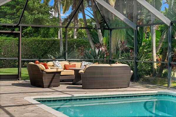 A covered outdoor seating area with a pool. - NEW! 3BR Park Shore Retreat w/ Large Pool & Patio (Naples)