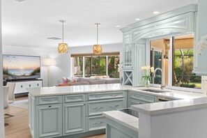 A modern kitchen with a large island, white cabinetry, and pendant lighting. - NEW! 3BR Park Shore Retreat w/ Large Pool & Patio (Naples)