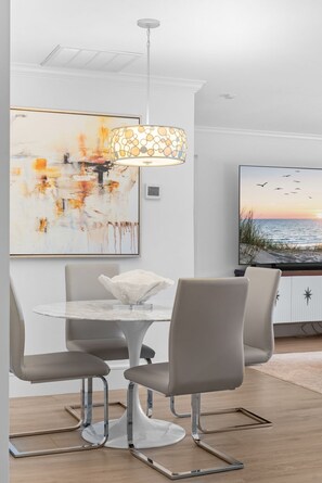 A modern dining area with a round table, four chairs, a decorative lamp, and a painting on the wall. - NEW! 3BR Park Shore Retreat w/ Large Pool & Patio (Naples)